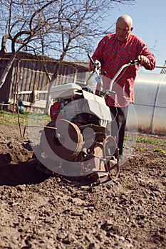 Man cultivates  land with  cultivator