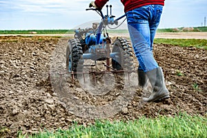 Man cultivating soil with tiller block in spring. photo
