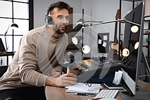 Man with cup of coffee working as radio host in modern studio