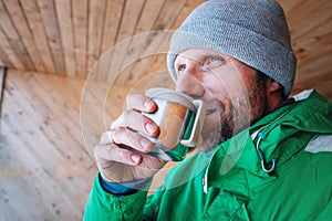 Man with cup of hot drink warms on open winter air photo