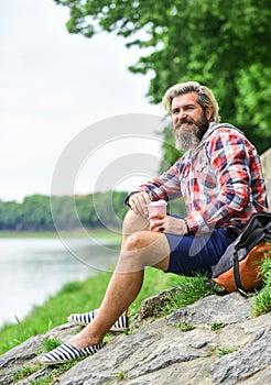 Man with cup outdoors. Man outdoors with cup of coffee. Drinking hot coffee. Enjoying nature at riverside. Guy with