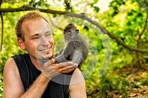 Man with a curious monkey on the shoulder in tropical forest