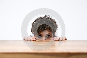 Man with curly hair peeking from behind the desk