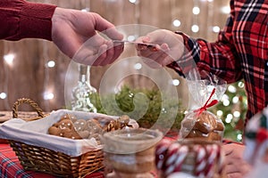 Man customer buying christmas sweets, gingerbread at the bakery giving credit card to the woman seller.