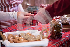 Man  customer buying hot chocolate in a paper cup, sweets at the christmas bakery giving credit card to the woman seller.