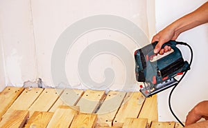 A man cuts a board with an electric saw. Repair of the floor in the house. Selective focus