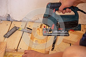 A man cuts a board with an electric saw. Repair of the floor in the house. Selective focus