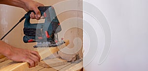 A man cuts a board with an electric saw. Repair of the floor in the house. Selective focus