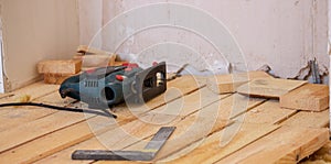 A man cuts a board with an electric saw. Repair of the floor in the house. Selective focus