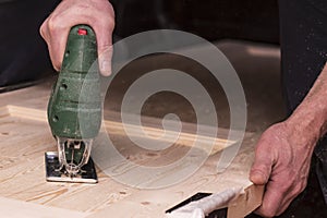 Man cuts a circle in a wooden door using an electric jigsaw joinery