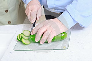 Man cuts cucumber in the kitchen