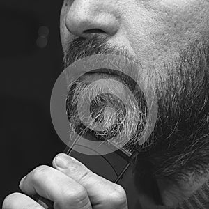 A man cuts his gray beard trimmer close-up