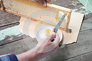 man cuts honeycombs from a honey frame with a knife for eating for tea, honey in honeycombs is good for the health