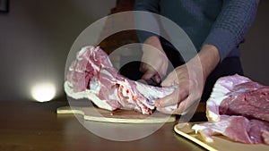 A Man Cuts Huge Pieces of Meat, Pork with a Kitchen Knife. Butchering Meat on a Cutting Board at Home, Home Kitchen