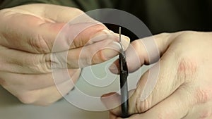 The man cuts an indefinite trims fingernails with nail scissors