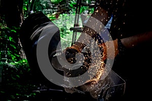 A man cuts metal using an angle grinder. Many sparks