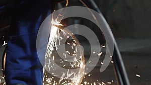 A man cuts a pipe with flame cutting torch to sparks in a workshop, slow motion