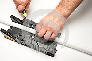 A man cuts a polystyrene baseboard with a clerical knife using a box to cut corners. Renovation work. Repair in the apartment.