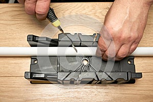 A man cuts a polystyrene baseboard with a clerical knife using a box to cut corners. Renovation work. Repair in the apartment.