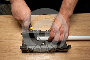 A man cuts a polystyrene baseboard with a clerical knife using a box to cut corners. Renovation work. Repair in the apartment.