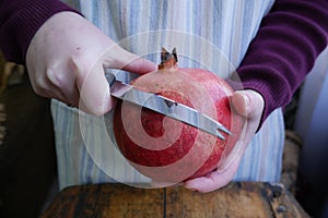 Man cuts a ripe pomegranate with a knif