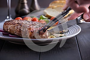 Man cuts steak from beef meat