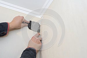 A man cuts the wallpaper with a clerical knife and a spatula. Apartment renovation, construction work