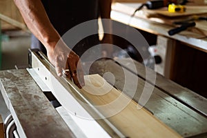 A man cuts wood on a circular saw in a carpenter workshop