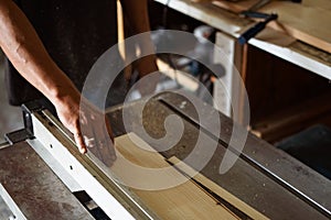 A man cuts wood on a circular saw in a carpenter workshop