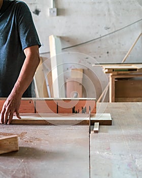 A man cuts wood on a circular saw in a carpenter workshop