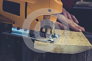 Man cuts wood products, using electric jigsaws outdoors. Close-up