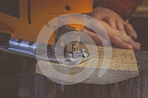 Man cuts wood products, using electric jigsaws outdoors. Close-up