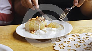 A man cuts zeppelins served in a plate with sour cream in a restaurant.