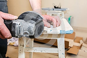 Man is cutting baseboard. Repair works indoors. Renovation in the flat.  Angle grinder in hands