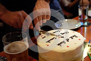 Man cutting birthday cake in dimmed light pub, birthday party concept