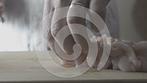 Man is cutting a chicken fillet on a wooden board. Video desaturate