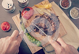 Man cutting and eating a grilled beef steak