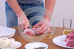 Man cutting fresh fillet meat pork on pieces to cook shashlik, hands closeup.