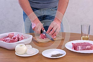 Man cutting fresh fillet meat pork on pieces to cook shashlik, hands closeup.