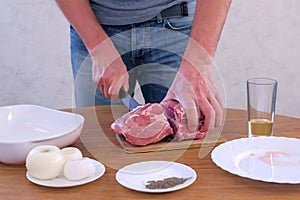 Man cutting fresh meat pork on pieces to cook shashlik, hands closeup.