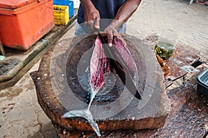 Man cutting fresh tuna with huge knife in Weligama In Sri Lanka.
