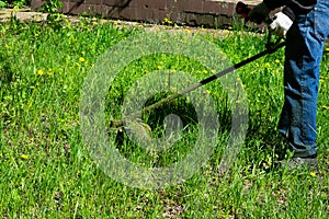 Man cutting grass at back yard using grass-cutter at summer season.