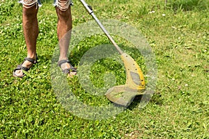 Man cutting the grass in the backyard with a lawn mower, trimmer, detail. Copy space