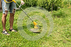 Man cutting the grass in the backyard with a lawn mower, trimmer, detail. Copy space