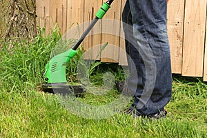Man cutting the grass with electric trimmer