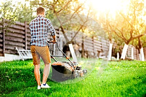 Man cutting grass in his garden using a gasoline powered lawn mower