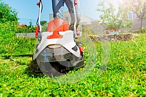 Man cutting grass using electric lawnmower in garden