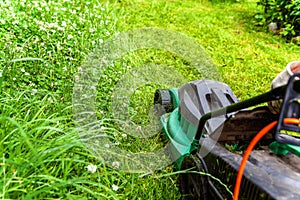 Man cutting green grass with lawn mower in backyard