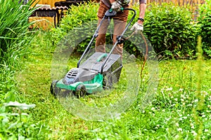 Man cutting green grass with lawn mower in backyard