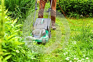 Man cutting green grass with lawn mower in backyard